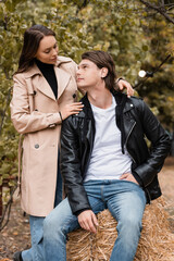 Fototapeta premium brunette woman in trench coat hugging stylish boyfriend in autumnal park.