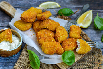 
 Crispy oven baked  chicken Nuggets  with garlic sauce.Breaded chicken fillets  with chilly peppers and fresh basil on wooden rustic background