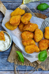 
 Crispy oven baked  chicken Nuggets  with garlic sauce.Breaded chicken fillets  with chilly peppers and fresh basil on wooden rustic background