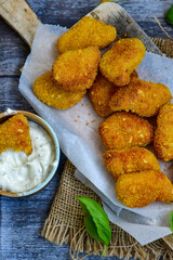 
 Crispy oven baked  chicken Nuggets  with garlic sauce.Breaded chicken fillets  with chilly peppers and fresh basil on wooden rustic background
