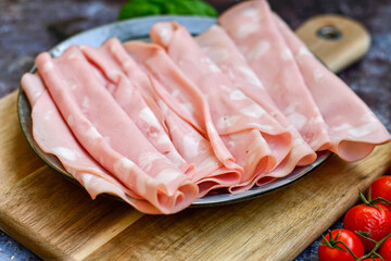 Slices Of  Traditional Italian antipasti mortadella Bolognese  on a wooden  cutting board.