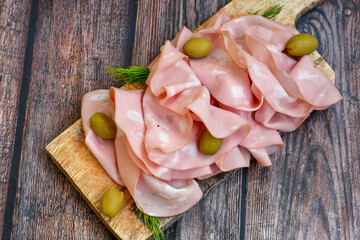 Slices Of  Traditional Italian antipasti mortadella Bolognese  on a wooden  cutting board