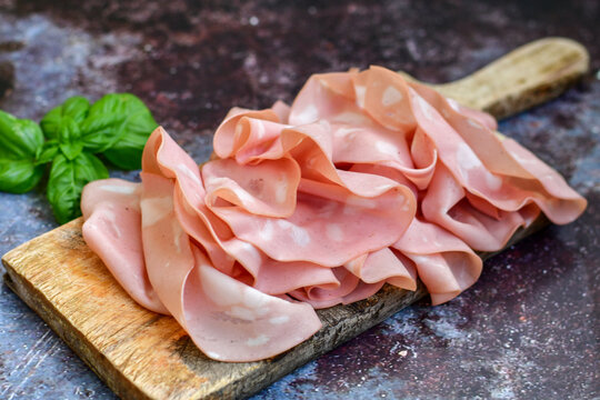 Slices Of  Traditional Italian antipasti mortadella Bolognese  on a wooden  cutting board.