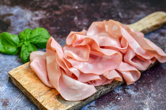 Slices Of  Traditional Italian antipasti mortadella Bolognese  on a wooden  cutting board.
