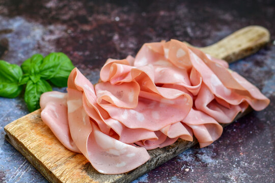 Slices Of  Traditional Italian antipasti mortadella Bolognese  on a wooden  cutting board.