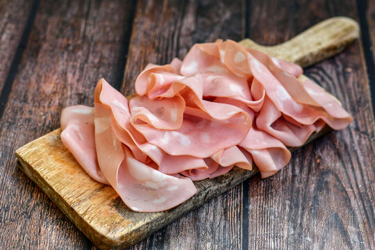 Slices Of  Traditional Italian antipasti mortadella Bolognese  on a wooden  cutting board