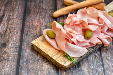 Slices Of  Traditional Italian antipasti mortadella Bolognese  on a wooden  cutting board