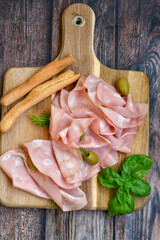 Slices Of  Traditional Italian antipasti mortadella Bolognese  on a wooden  cutting board © Striker777