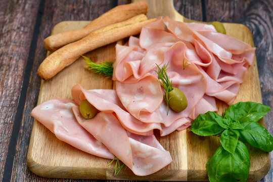 Slices Of  Traditional Italian antipasti mortadella Bolognese  on a wooden  cutting board