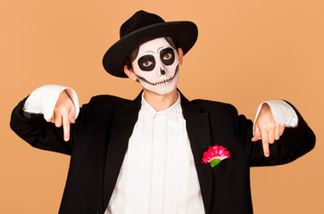Man wearing day of the dead costume over background pointing down, indicating direction with fingers