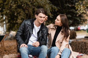 smiling young woman adjusting wired earphone in ear of happy boyfriend.