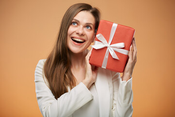 Happy woman in white suit holding red gift box looking up. Isolated female portrait.