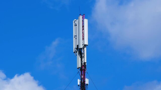Cell site antenna on a blue sky and white clouds background. Cell tower with mobile Telecommunications equipment. Cellular tower base station with electronic communications equipment. Place for text