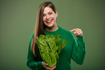 Woman points finger at romaine lettuce salad. Advertising female portrait on green.