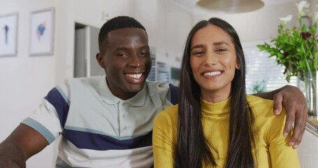 Video of happy diverse couple making video call smiling and waving to camera in kitchen - Powered by Adobe