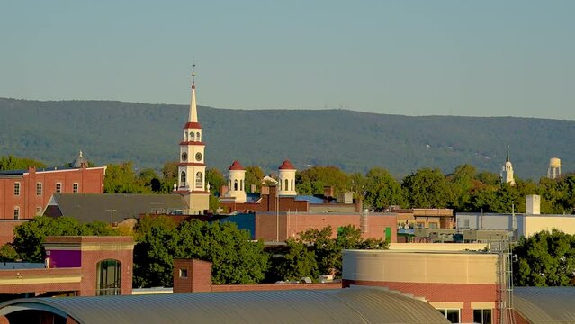 View of church spires in the city of Frederick, Maryland with trees and a hill in the background.