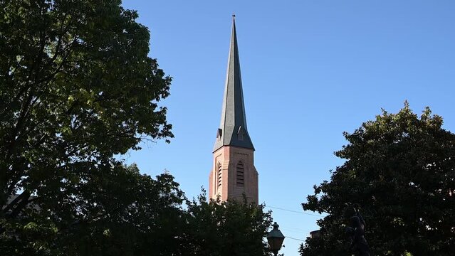 Church spire in Frederick, Maryland with trees and a blue sky in the background.