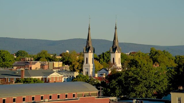 View of church spires in Frederick, Maryland with a hill and the sky in the background.