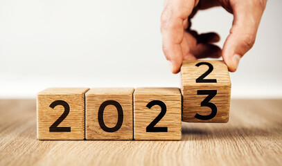 Happy new year concept. Flipping of wooden cube block change from 2022 to 2023.
