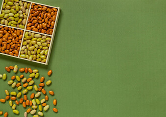 Wooden box with yellow and green beans on a yellow background. Phaseolus vulgaris. Top view. Copy...