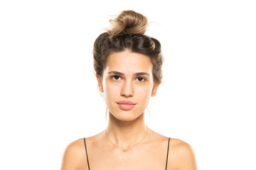 woman with messy loose bun and no makeup on a white studio background. front view