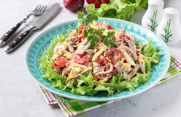 Salad with tongue, sweet peppers, eggs, cheese and lettuce leaves on blue plate on gray background, Close up