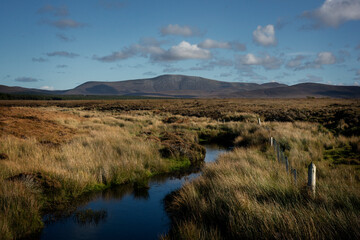 A small stream flows through the moorland of Aughness, Ballycroy, Ireland. On the horizon the mountains of Wild Nephin National Park