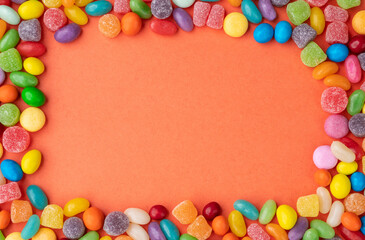 Obraz premium Frame of colorful candies over orange background with copy space