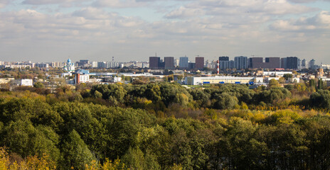 Obraz premium Panoramic top view of the city of Moscow with buildings among the lush foliage of autumn trees on a sunny cloudy October d