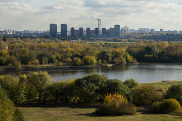 Fototapeta premium Panoramic top view of the city of Moscow with buildings among the lush foliage of autumn trees and the river on a sunny cloudy October day