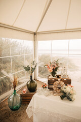 Beautiful vases with flowers on the beach. Wedding in a marquee on the beach. Decoration for wedding by the sea