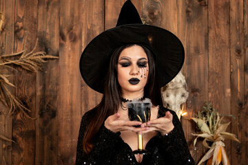 young girl in the image of a witch, wearing a black hat and a black dress with a make-up