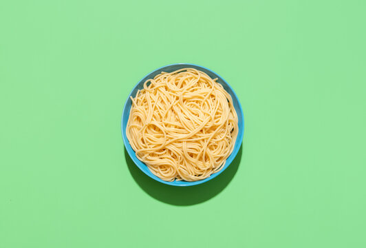 Spaghetti top view on a green background. Cooked pasta without sauce.