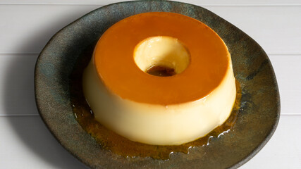 traditional pudim or pudding brazilian dessert or known as flan, top view close up over table, dark dish on the table