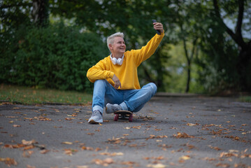 A woman sits on a skateboard and looks into her phone and does salfy