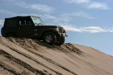 Fototapeta na wymiar Lima, Peru; June 2014: Jeep Wrangler doing some off road driving in the Peruvian dessert with some dunes.