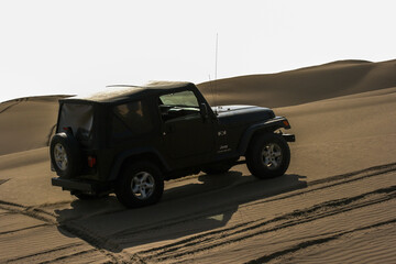 Fototapeta na wymiar Lima, Peru; June 2014: Jeep Wrangler doing some off road driving in the Peruvian dessert with some dunes.