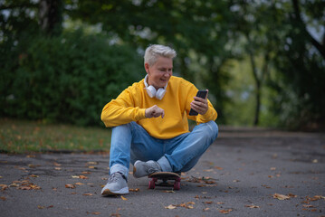 A woman sits on a skateboard and looks into her phone and does salfy