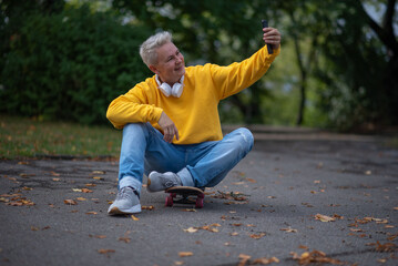 A woman sits on a skateboard and looks into her phone and does salfy