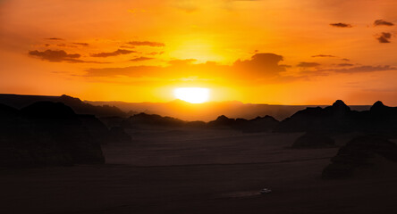 Fototapeta na wymiar A speeding car in the desert at sunset.
