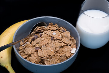 A bowl of bran flakes with dried fruit including banana and raisins