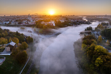 earlier foggy morning and aerial panoramic view on medieval castle and promenade overlooking the old city and historic buildings near wide river