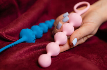Woman holding anal balls in bed close-up.