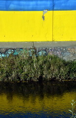 Mauer in Ukraine-Farben spiegelt sich im Wasser