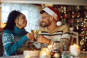 Happy couple toasting with wine at dining table during Christmas.