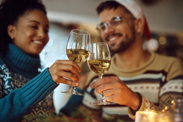 Close up of couple toasting with wineglasses while celebrating Christmas at home.