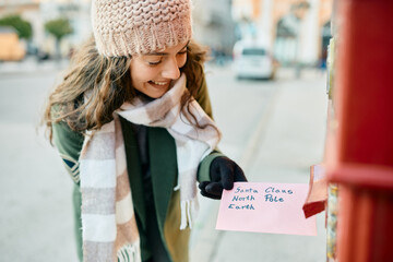 Happy woman has fun while sending letter to Santa.