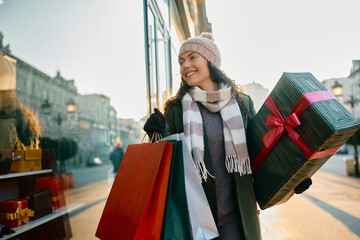 Happy woman window shopping during Christmas holidays in city.