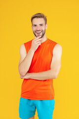 Fototapeta na wymiar Happy athlete isolated on yellow. Athletic man stroking chin studio. Sporting man in sportswear