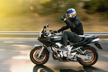Side view of a motorcycle rider riding on the highway road with motion blur.